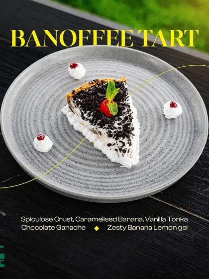 A slice of our decadent Banoffee Tart, featuring a speculoos crust, caramelized banana, and chocolate ganache.