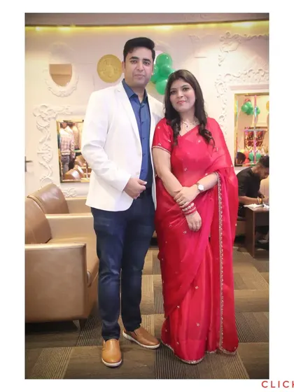 A full-length portrait of a couple at an event, dressed in smart-casual attire.
