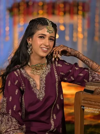 A smiling bride posing for the camera, her mehandi looking stunning.