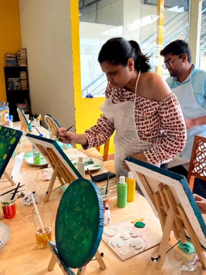 A participant at a Koi Fish painting workshop, carefully adding details to her canvas.