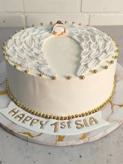 A heavenly cake for a first birthday. This design features beautiful, handcrafted angel wings and a delicate halo, all finished with gold pearl details for a touch of elegance.