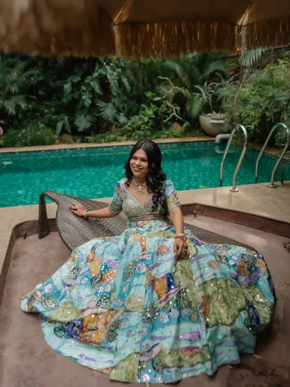 A beautiful bride in her colorful lehenga, sitting by the pool. We use the venue's features to create unique and stylish portraits.