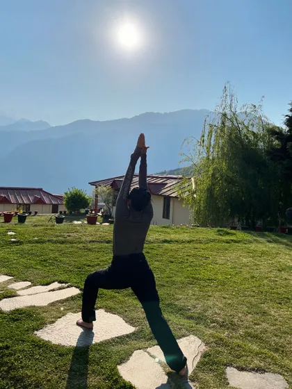 A strong and steady Virabhadrasana I, or Warrior I, against the backdrop of the serene Himalayan landscape. This pose builds strength in the legs and focus in the mind, perfect for a morning practice.