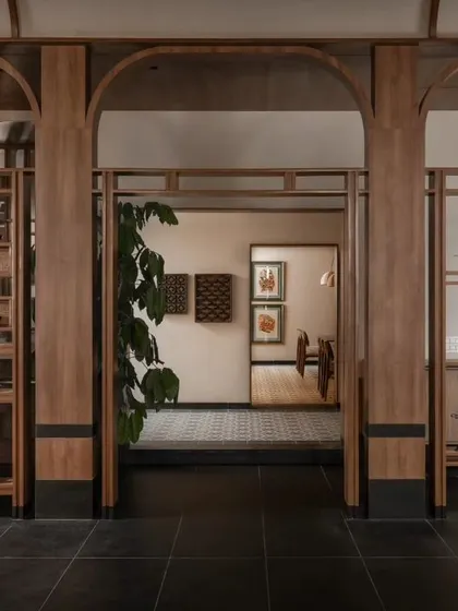 Looking through the wooden archways into another section of the restaurant. This framing technique creates intriguing sightlines and adds depth to the overall interior design.