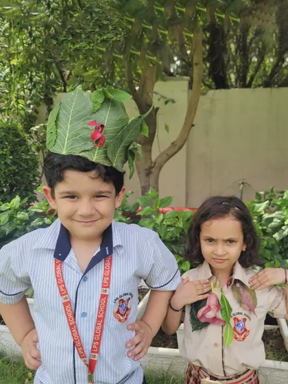 Two students proudly wear their handmade nature crowns and necklaces, spreading the message of environmental conservation with joy.