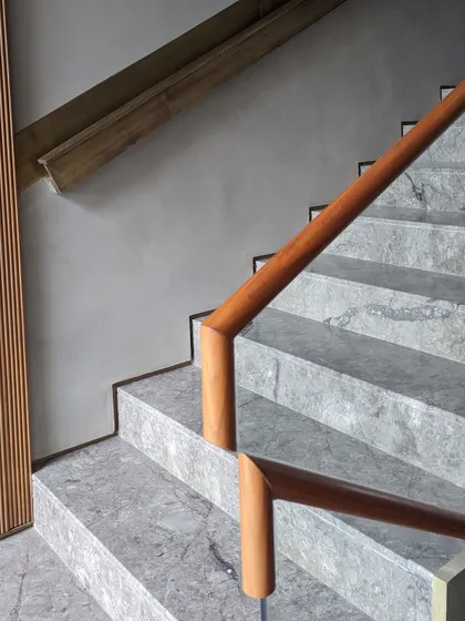 The main staircase features a beautiful interplay of materials, with grey marble steps and a warm wooden handrail. The design is clean and modern, yet feels timeless and elegant.