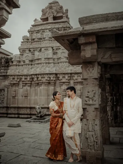 A quiet, shared look between the couple, framed by the intricate carvings of the temple.