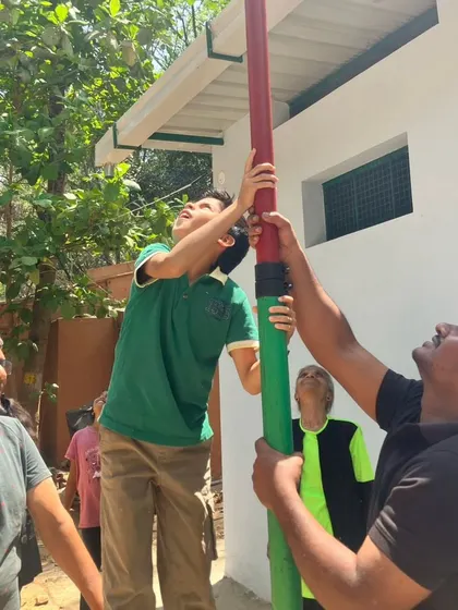 An instructor guides a child in using a long pole, a tool used to safely rescue birds from high places. This is a practical lesson in problem-solving and animal welfare.