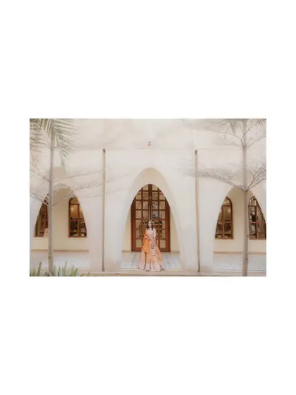 A wide, artistic shot of the bride standing before a grand archway. I use architectural elements to create dramatic and memorable bridal portraits.