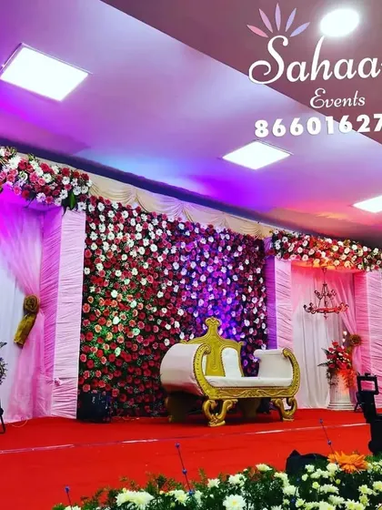 A lavish reception stage with a full wall of red and white roses. The dramatic floral backdrop is paired with elegant drapery and a classic golden-white settee for a truly grand statement.