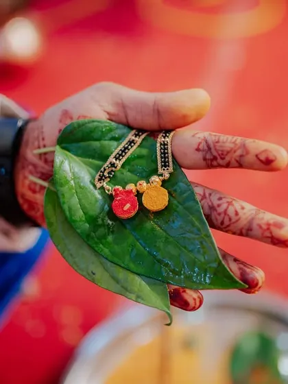 A detail shot of the Mangalsutra resting on a betel leaf in the groom's hand, just before being tied.