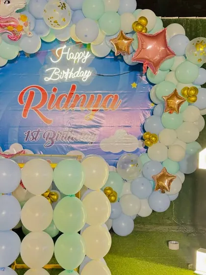 A dreamy unicorn-themed first birthday. This setup features a circular balloon arch in pastel colors, a custom backdrop, and a light-up marquee number '1'.
