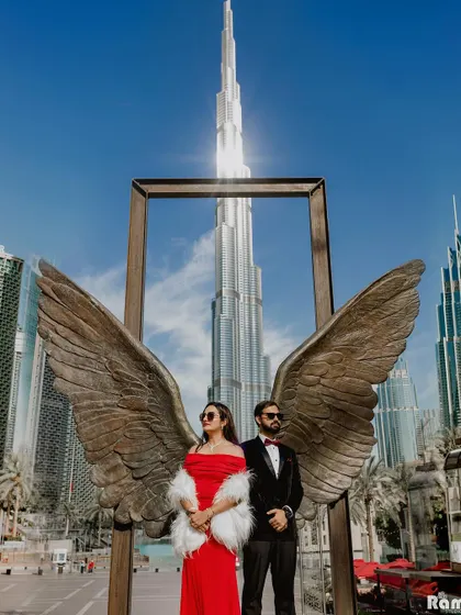 For a touch of modern glamour, we can take our story to international cityscapes. This shot in Dubai, using the iconic Burj Khalifa and the famous angel wings sculpture, creates a powerful and aspirational pre-wedding image.