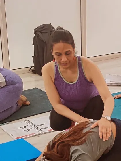 A close-up of a tactile cue during a shell stretch. This kind of gentle guidance helps students feel the intended stretch and spinal articulation, a technique they will learn to apply with their own clients.
