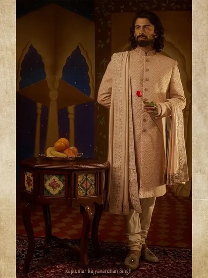 Styling for Rajkumar Rajyavardhan Singh. His look is softer, with a blush-pink sherwani and a single rose, suggesting a more romantic and thoughtful character within the royal court.