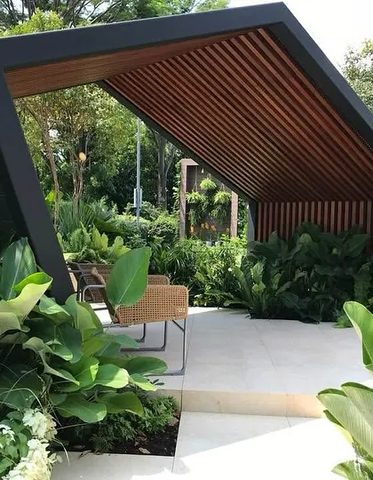 The architectural gazebo in this garden serves as a perfect outdoor living room. We surrounded it with large-leafed plants like Philodendron to create a sense of enclosure and privacy.