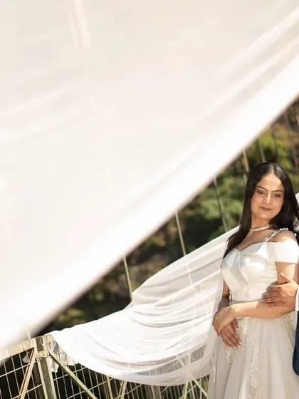 The delicate, sheer fabric of the veil trail creates a beautiful, soft-focus effect in this romantic pre-wedding portrait.