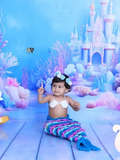A baby mermaid sits up, ready to play with her underwater friends. The rocking seahorse and unicorn add a playful touch to this fantasy-themed shoot.