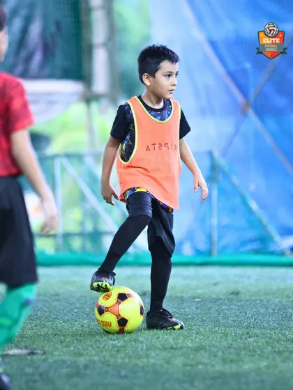 Composure on the ball. A young player stands ready with the ball at his feet, learning to stay calm and aware of his surroundings during practice matches.