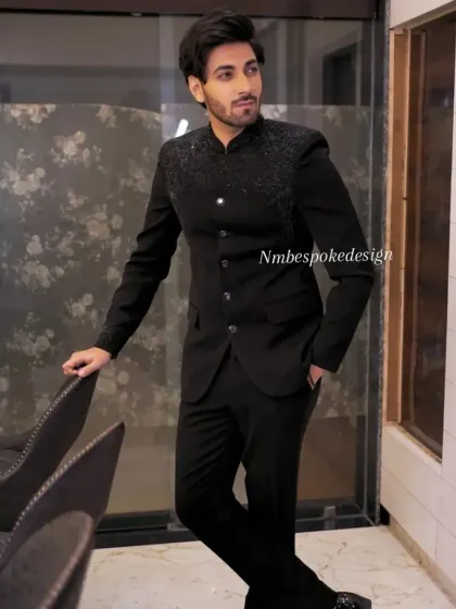 A client wearing a classic black Jodhpuri suit with subtle, sparkling black beadwork on the shoulders. This is a perfect outfit for a cocktail night or reception.