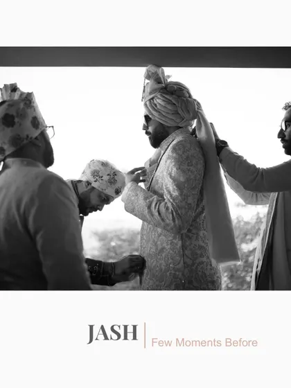 A black and white shot of the groom getting ready, with his family helping him tie his turban.