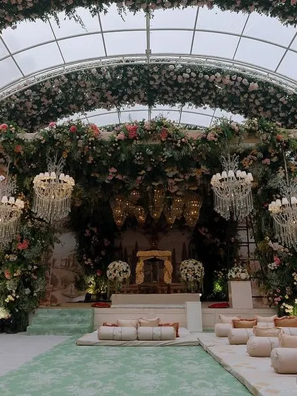 A wide shot of the breathtaking Anand Karaj ceremony space. The transparent arched roof is covered in flowers, creating the feeling of being in a grand, open-air floral cathedral.