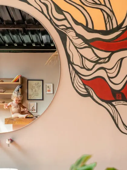 Art and reflection are woven into the design of Unallome. A large, circular mirror reflects a custom mural, adding a layer of creative expression to the bathroom space while maintaining a connection to the earthy, organic aesthetic.