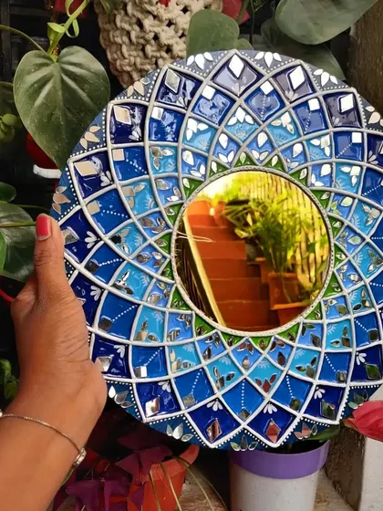 A beautiful Lippan art mirror with a mosaic-like pattern in shades of blue. The mirror work is incredibly detailed, creating a mesmerizing effect.