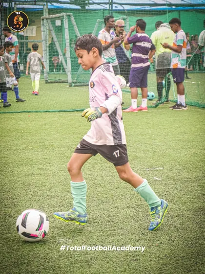 A young goalkeeper in action, showing focus and control as he moves with the ball.