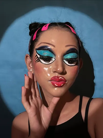 The lighting in this shot highlights the 'glass skin' effect, showing a completely smooth and reflective surface, which is a key component of this pop art makeup style.