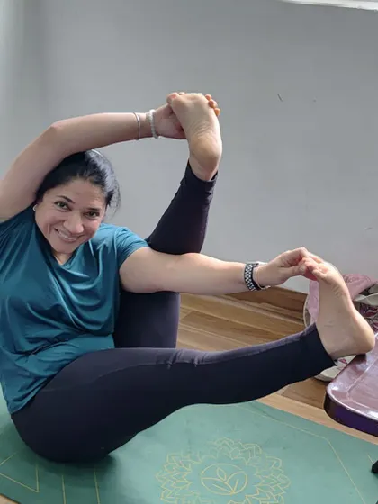 A student holds a complex seated hip-opening pose, showing incredible flexibility and focus.