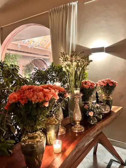 An elegant console table arrangement inside, with candles and vases of pink roses.
