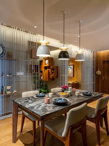 The dining area is subtly demarcated by a screen of slender vertical metal rods, which provides a sense of separation without obstructing light or views. A marble-topped dining table adds a touch of elegance against the engineered wood flooring.