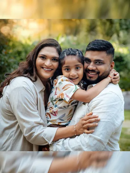 A classic family portrait taken outdoors, surrounded by lush greenery. The natural setting adds a warm and relaxed feel to this beautiful picture of a happy family.
