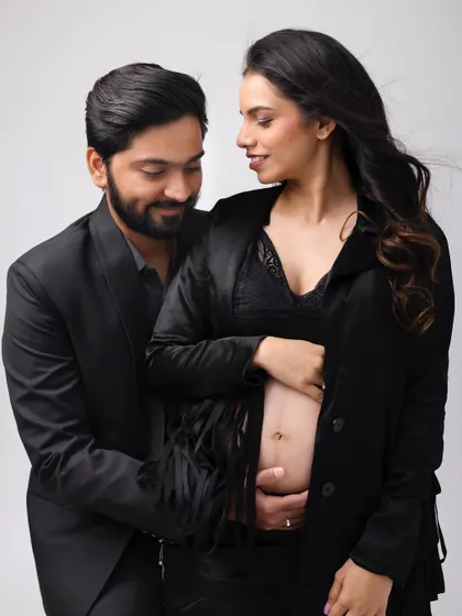 A tender moment between the parents-to-be. Her makeup is soft and natural, highlighting her pregnancy glow.