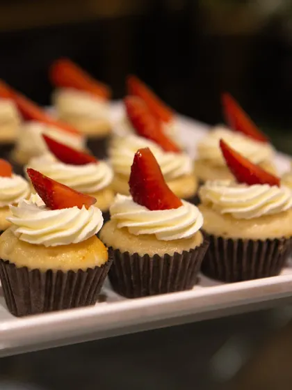 A close-up of our classic vanilla cupcakes with strawberry garnish. The simplicity of the presentation allows the quality of the ingredients to shine.