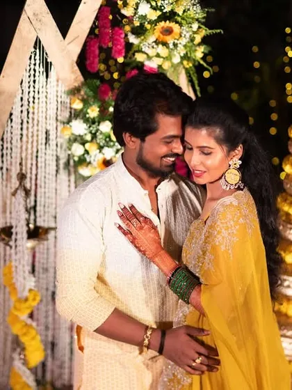 A romantic portrait of the couple against a backdrop of marigolds and fairy lights at their evening Haldi event.