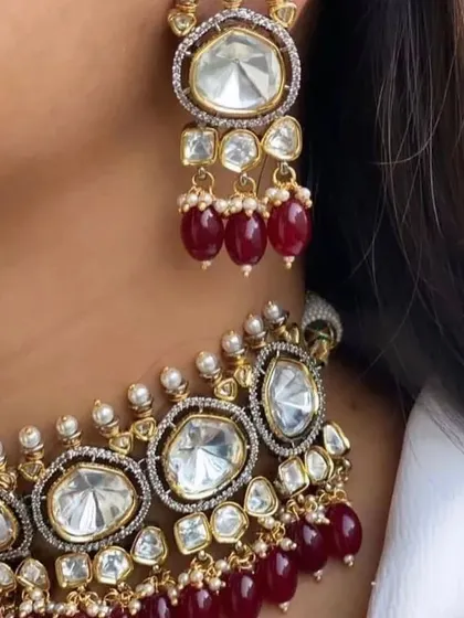 A close-up view of a beautiful ruby red kundan necklace set. You can see the fine setting of the uncut stones and the small pearls that add to its elegance. This is a classic choice for any traditional event.