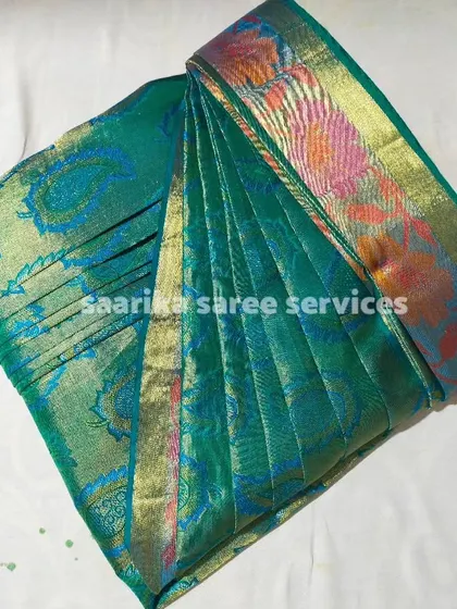 The intricate weave of this green brocade saree is highlighted by the neat pleats. It's now ready to be the star of any event.