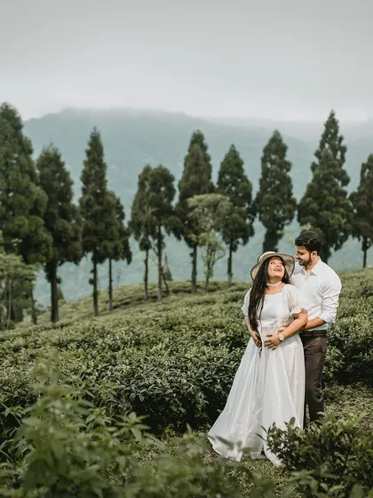 A beautiful portrait of a couple in a Darjeeling tea garden, with the bride wearing a lovely hat. The mountains in the background add to the scenic beauty of this destination pre-wedding shoot.
