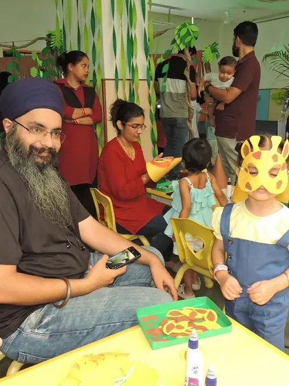 A parent and child, dressed in a giraffe mask, enjoy a craft activity during our 'Jungle Joyland' themed event.