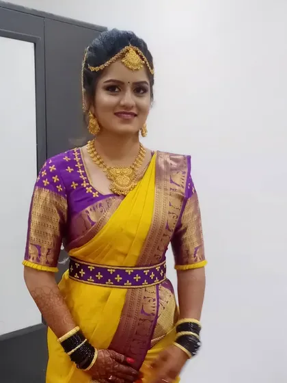 A full view of the bride in her yellow and purple saree. This photo shows the complete look, including the matching embroidered belt and perfectly pleated saree, ready for her wedding ceremony.