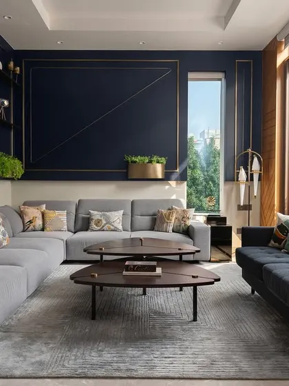 This modern luxury residence showcases a harmony of bold elegance and playful creativity. The living area is defined by a deep blue feature wall with brass inlays, paired with contemporary furniture and ample natural light to create a space that nurtures family life.