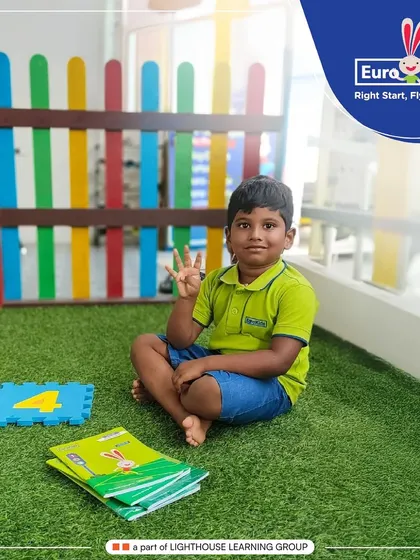 A young student proudly shows the number four with his fingers while sitting next to a number puzzle. My approach makes learning math concepts like quantity and numerals intuitive and engaging.