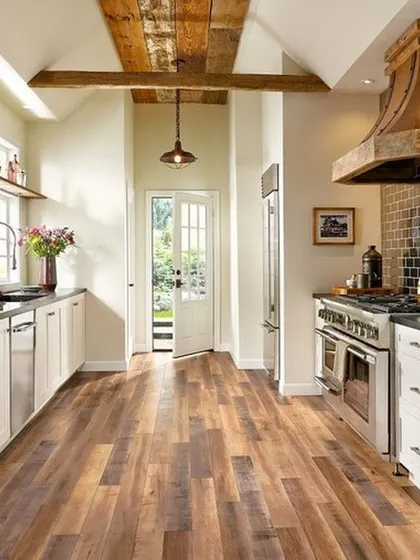 This kitchen showcases a rustic, multi-toned wood floor that adds immense character. It complements the farmhouse sink and exposed wood beams, proving that hardwood is a practical and beautiful choice for kitchens.