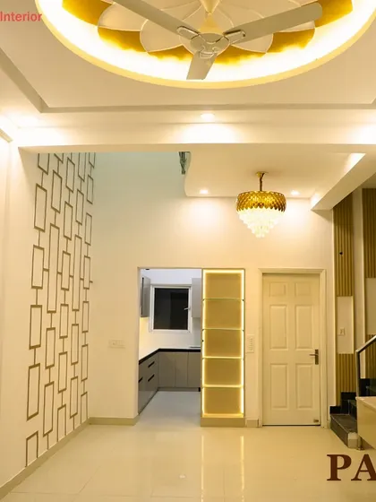 A view of a luxurious living space with a royal theme, featuring a unique flower-shaped ceiling design with backlighting and an elegant chandelier.