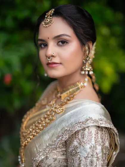A close-up capturing timeless beauty. This South Indian bridal makeup features a flawless base, defined eyes with a classic wing, and a traditional bindi, all complementing her intricate gold jewellery.