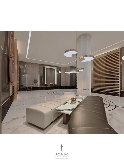A seating area within the foyer provides a place to pause and appreciate the surroundings. The modern pendant lights and slatted wood screen add layers of texture and warmth to the marble-clad space.