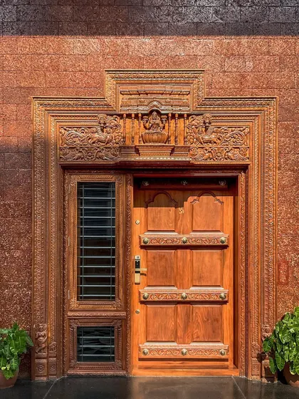 The main entrance door of the villa is a work of art in itself. The heavily carved wooden frame and door, set against a textured brick wall, signal the home's commitment to craftsmanship and luxury from the moment you arrive.