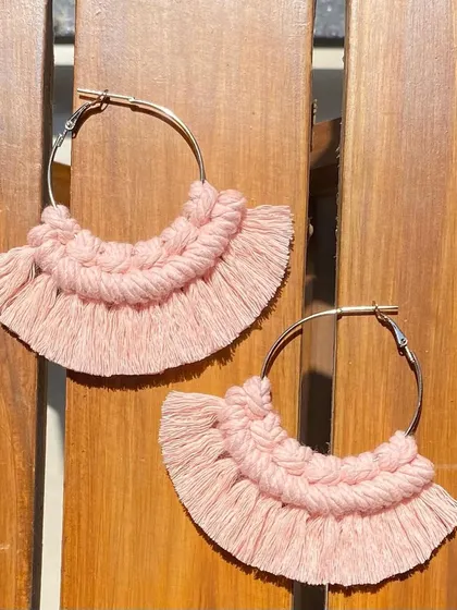 A product shot of our boho fringe earrings against a wooden background. The contrast highlights the soft texture and intricate knotting of the pink macrame.